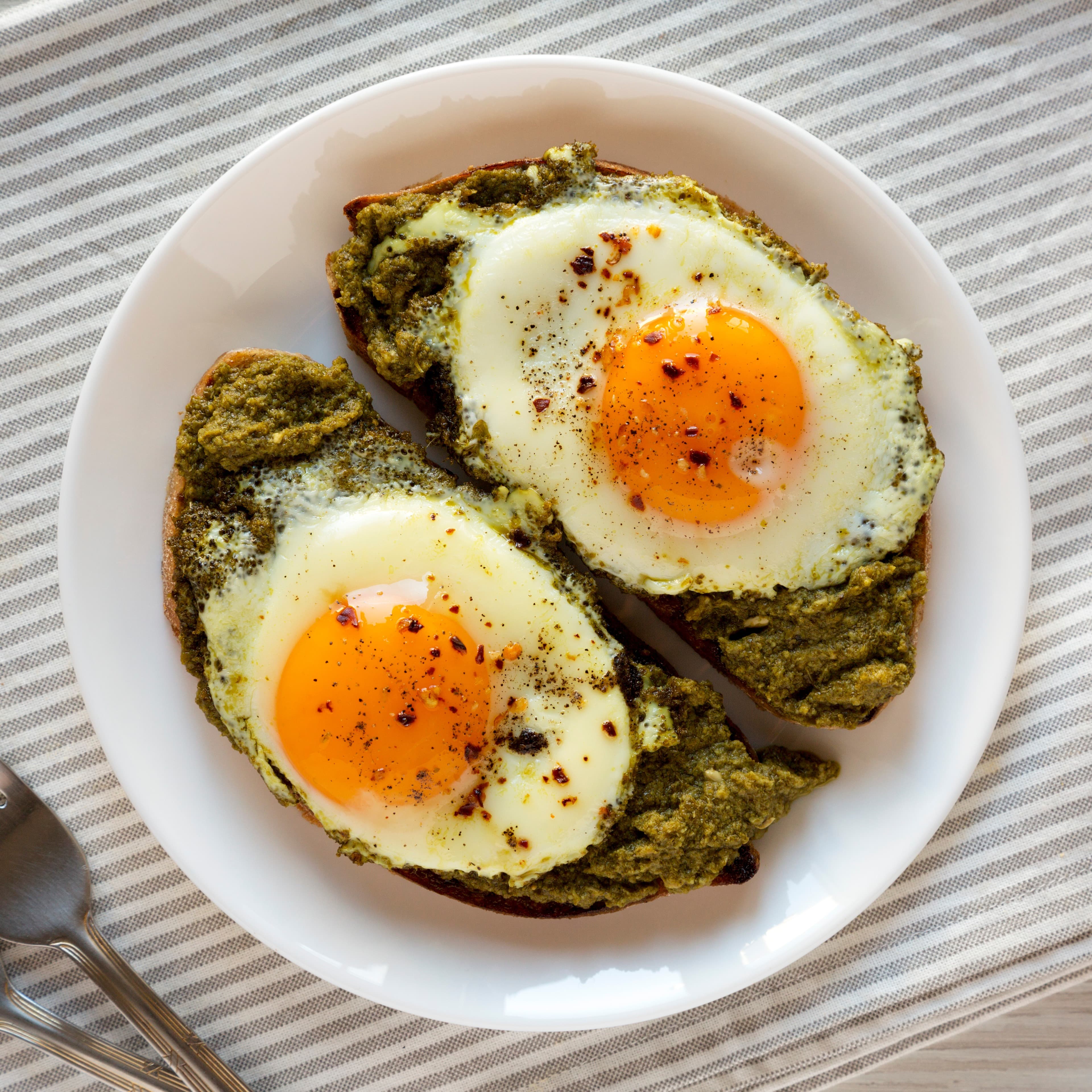 Pesto egg toast. Runny eggs with black pepper on a pesto base.