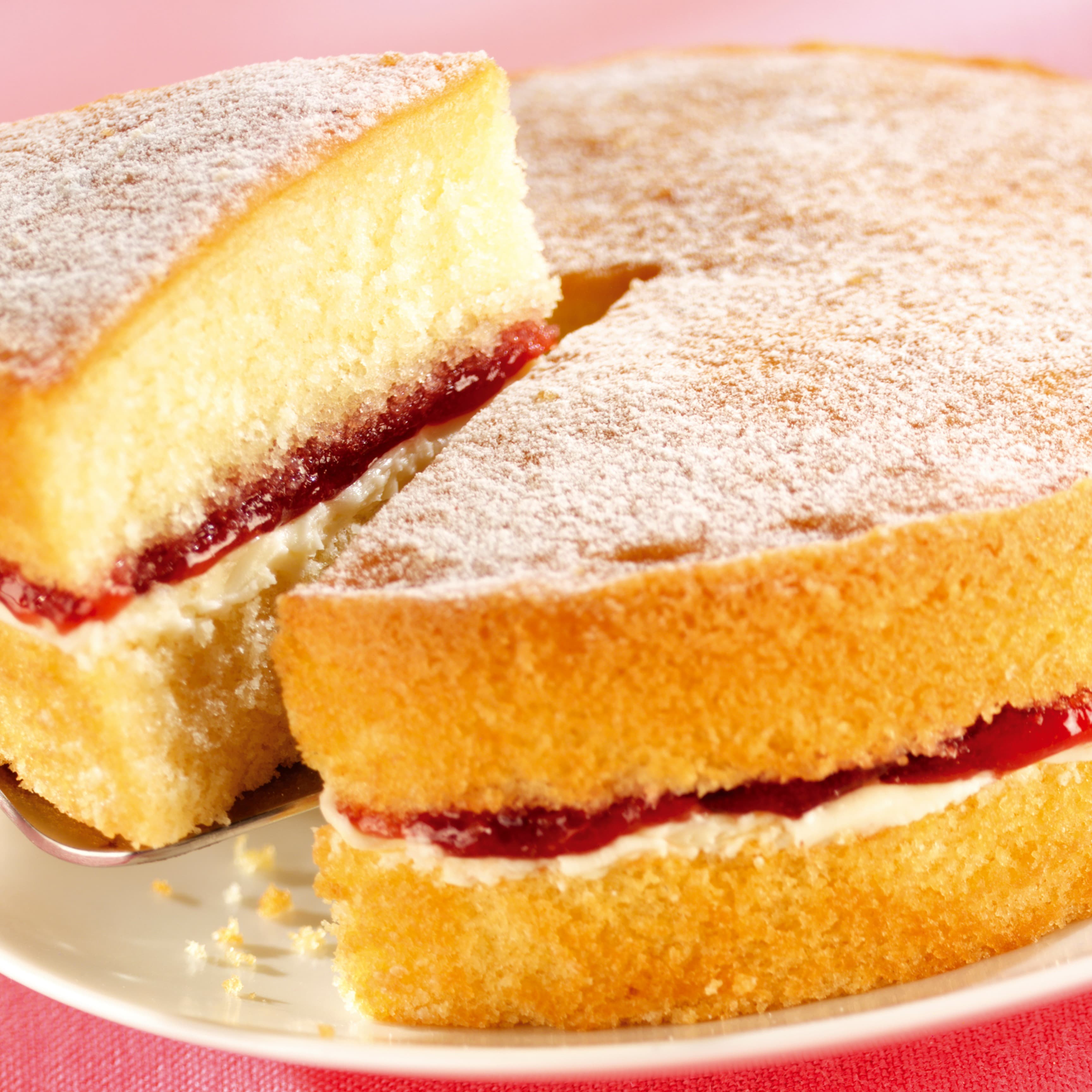 Victoria sponge cake filled with jam and cream with powdered sugar sprinkled on the top a British classic.